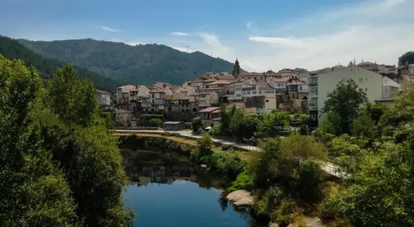 Un pueblo con tejados rojos y casas blancas se alza sobre un río tranquilo. Un lugar perfecto para descubrir qué ver en Ribadavia.