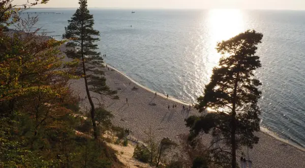 Zachód słońca nad Bałtykiem, złocący piaszczystą plażę i majestatyczne klify na wyspie Wolin.