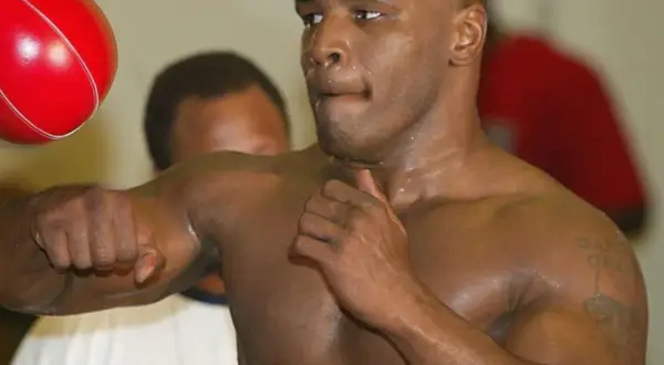 Mike Tyson trains with a speed bag, his intense focus evident. The red bag is a blur as he lands punches, a testament to his legendary boxing skills.
