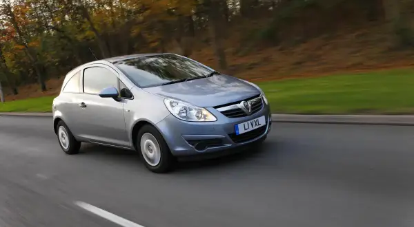 Srebrny Opel Corsa D 1.2 benzyna w ruchu, z rozmytym tłem jesiennego lasu.