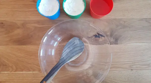 Zutaten für das Oobleck-Rezept: Mehl in blauen und grünen Bechern, Wasser im roten Becher und eine Schüssel mit Löffel.