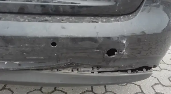 Uszkodzony zderzak po uderzeniu parkingowym: wgniecenia, pęknięcia i widoczne objawy uszkodzonych ślizgów zderzaka.