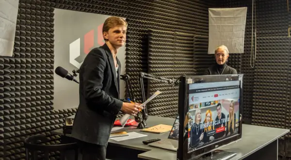 Młody mężczyzna z dokumentami w ręku i starsza kobieta w studiu radiowym. Rozmawiają o tym, czy po technikum można iść na studia.