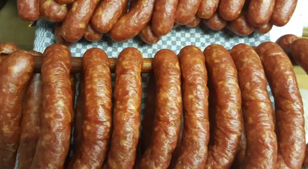 Gotowy przepis na kiełbasę swojską 5 kg. Wędliny wiszą na drewnianych kijach, gotowe do dalszej obróbki.