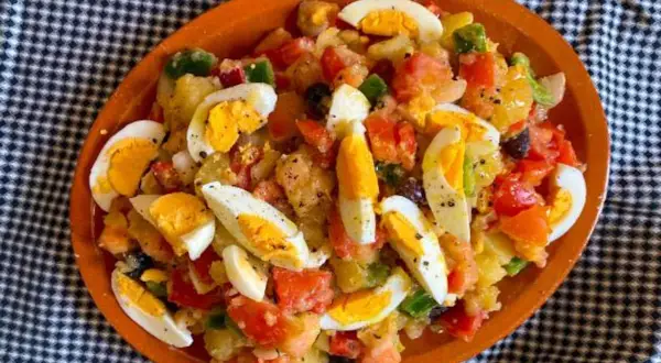Deliciosa ensalada de patatas de verano con huevos duros, tomates, pimientos y aceitunas.