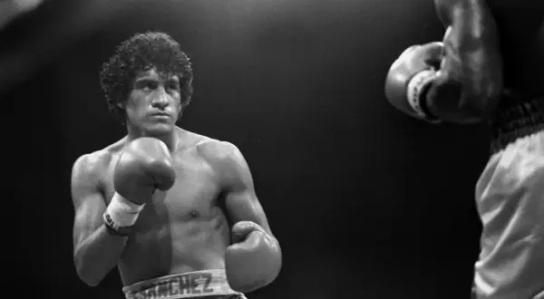 Salvador Sanchez, a legendary boxer, stands ready in the ring, his reach evident as he faces an opponent.