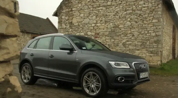 Szary Audi Q5 Quattro zaparkowany przy kamiennym budynku.