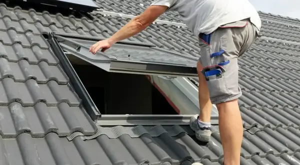 Instalacja okna dachowego na szarym dachu.