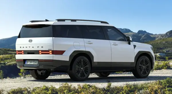 Biały Hyundai Santa Fe 2025 z czarnymi felgami na tle górskiego krajobrazu.