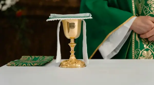 Złoty kielich i zielona stuła kapłana podczas post eucharystyczny.