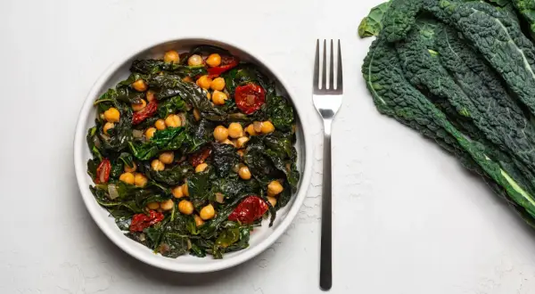 Piatto invitante con cavolo nero, ceci e pomodorini secchi, un'idea per una cavolo nero ricetta sana e gustosa.