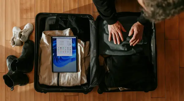 Pakowanie bagażu podręcznego: ubrania, buty i tablet do walizki.