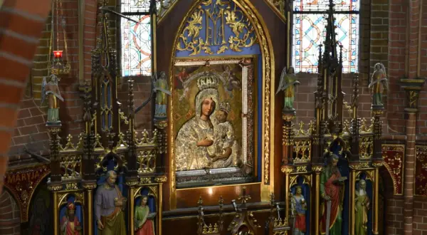 Ołtarz z obrazem Matki Boskiej, symbol objawień maryjnych w Polsce. Witraże i rzeźby dopełniają sakralny wystrój.