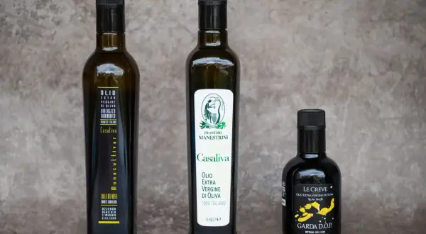 Tre bottiglie di olio extra vergine d'oliva, tra cui un Casaliva monocultivar e uno con etichetta "Le Creve Garda D.O.P.".