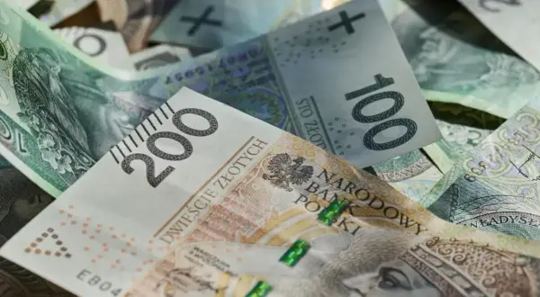 Złote banknoty 100 i 200 zł, symbolizujące średnią pensję w Polsce.
