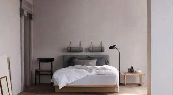 Minimalistisches Schlafzimmer mit Holzbett, grauem Kopfteil und zwei Wandrollen. Perfekte Inspiration schlafzimmer einrichten für Ruhe und Stil.