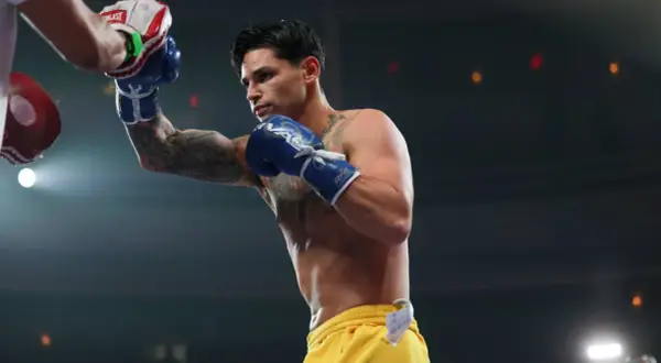 Ryan Garcia trains with a punching bag, his blue gloves a blur of motion.