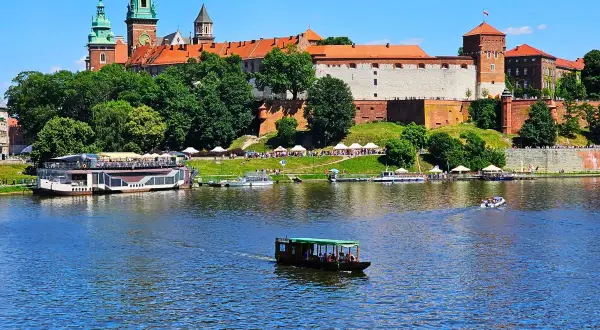 Krakau Sightseeing: Wawel-Schloss thront über dem Fluss mit Booten, die vorbeifahren.
