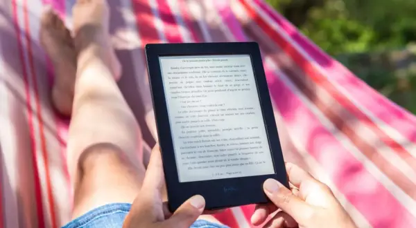 Osoba relaksuje się w hamaku, czytając e-booka. Idealny sposób na wakacje, gdy szukasz najlepszego czytnik ebook ranking.