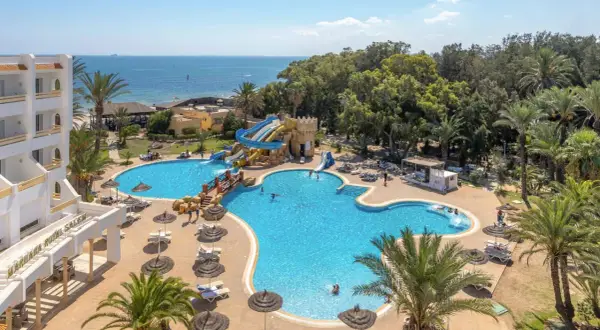 Basen z wodnymi zjeżdżalniami i palmami przy hotelu Marhaba Royal Salem.