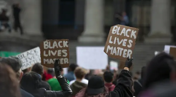 Ludzie protestują przeciwko rasizmowi, trzymając transparenty "Black Lives Matter".