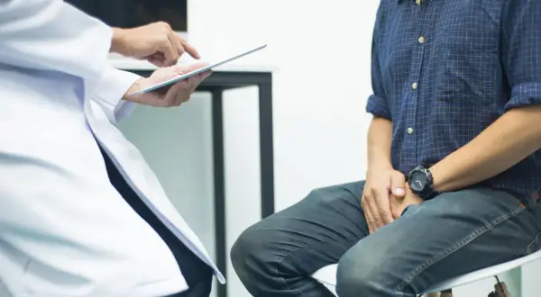 Lekarz pokazuje pacjentowi wyniki badań na tablecie. Czy biopsja oznacza raka? Pacjent z niepokojem czeka na diagnozę.