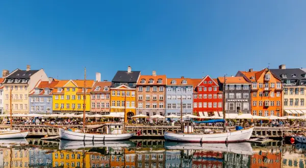 Bunte Häuser am Nyhavn, ein Kopenhagen must see. Boote spiegeln sich im Wasser.