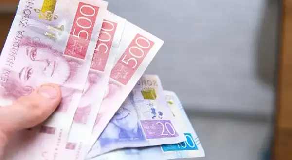Dłoń trzyma szwedzkie korony. Czy w Szwecji można płacić euro? Nie, używa się tam własnej waluty.