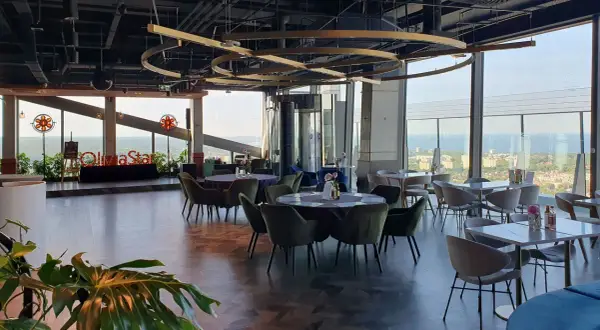 Eleganckie wnętrze restauracji Olivia Star z widokiem na miasto i morze. Stoły nakryte, gotowe na przyjęcie gości.