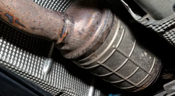 Podwozie samochodu z widocznym, zardzewiałym elementem układu wydechowego. Czy diesel ma katalizator? Tak, ten element to właśnie katalizator.