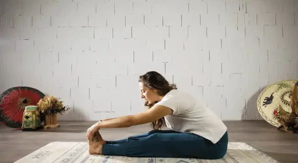 Mujer en postura de yoga Paschimottanasana, explorando el hatha significado de la calma y la conexión.