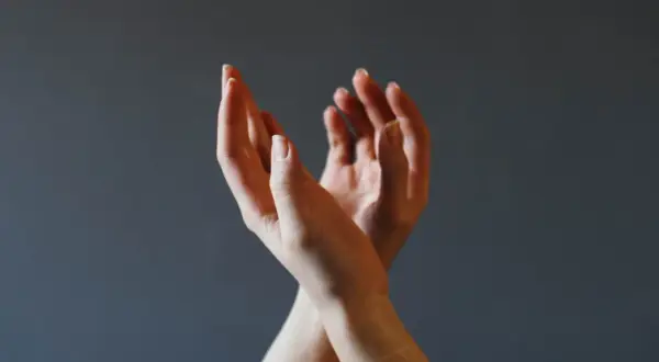 Dłonie splecione w geście, który może symbolizować trudności w wyrażaniu emocji, ale też potencjał do rozwoju psychomotoryki.