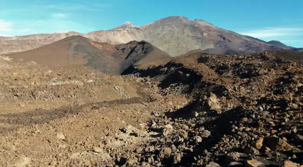 Paisaje volcánico árido visto desde el mirador de Samara, con montañas y conos de ceniza bajo un cielo azul.