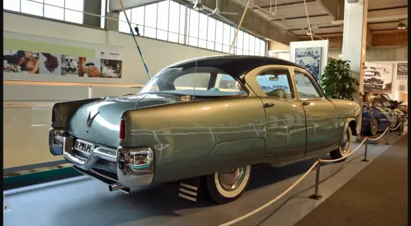 A vintage Volvo sedan, light green with a dark roof, is displayed indoors.