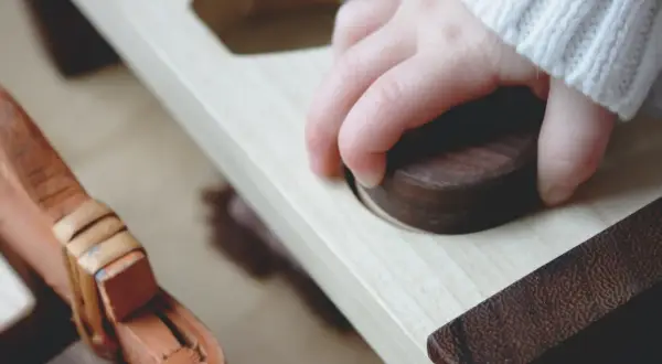 Mano de niño explorando un juguete de madera, un ejemplo del método Montessori para el desarrollo sensorial.