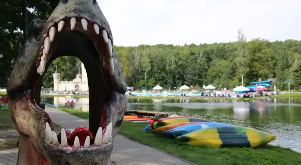 Przez paszczę dinozaura widać zamek i basen. To jedne z magicznych miejsc opolskich, gdzie czeka wodna zabawa i kajaki.