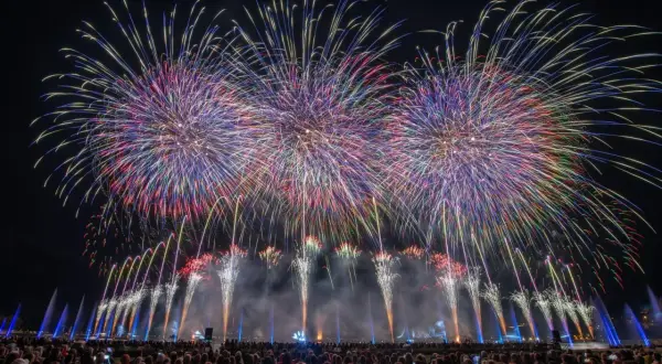 Spectacle pyrotechnique grandiose pour la fete du lac, illuminant le ciel nocturne de gerbes multicolores au-dessus d'une foule admirative.