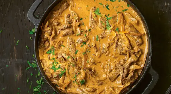 En krämig biff stroganoff i en gjutjärnspanna, toppad med färsk persilja.