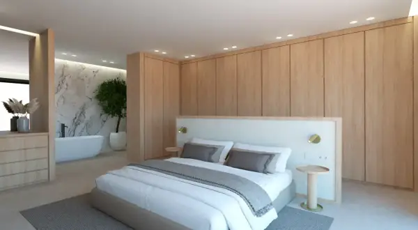 Dormitorio moderno con cama king size, armarios de madera y un baño suite con bañera exenta y pared de mármol.