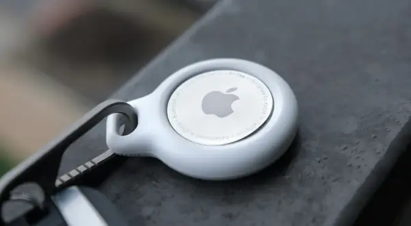 Biały AirTag od Apple, z logo i napisem "Designed by Apple in California". To urządzenie, które pomoże Ci odnaleźć zgubione przedmioty.