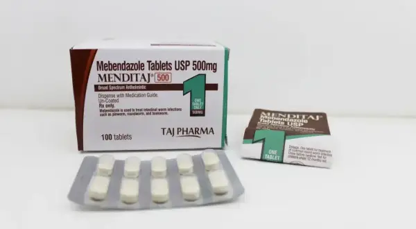 Opakowanie i blistry tabletek Mebendazolu USP 500mg na białym tle.
