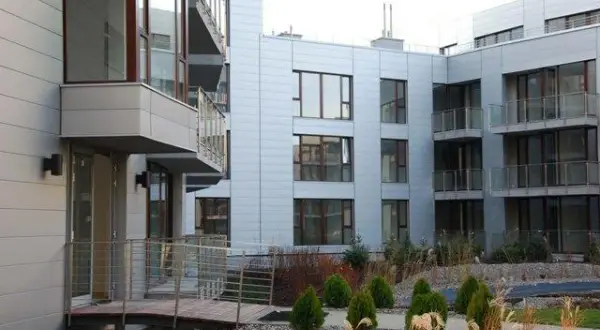 Nowoczesne budynki mieszkalne Triton Park Apartments z balkonami i dużymi oknami, otoczone zadbaną zielenią.