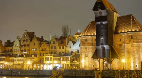 Gdańsk nocą, z Żurawiem i kamienicami odbijającymi się w wodzie.