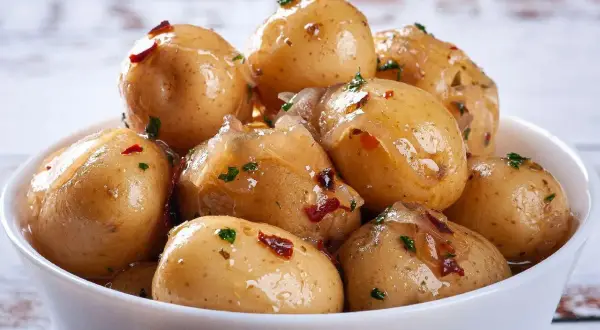 Miseczka pełna pysznych, błyszczących kiszonych ziemniaków z dodatkiem ziół i papryczki chili. Idealne jako dodatek do obiadu.
