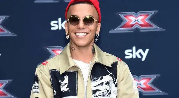 Artista con cappellino rosso e occhiali da sole, pronto a cantare le canzoni trap più famose.