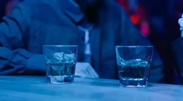 Dwa drinki na barze, a obok siedzi osoba. Czy można pić alkohol po radioterapii? To pytanie nurtuje wielu pacjentów.
