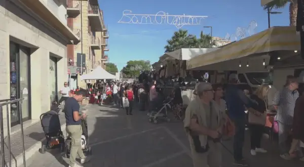 Festa San Crispino a Porto Sant'Elpidio: bancarelle affollate, gente che passeggia e acquista sotto un cielo azzurro.