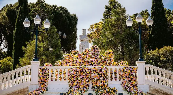 Escaleras adornadas con miles de flores vibrantes, donde zgz florece en un espectáculo de color. Una estatua real preside la escena.