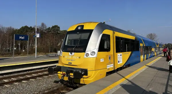 Pociąg TLK z żółto-niebieskimi pasami na stacji Hel, gotowy do podróży przez malownicze wydmy.