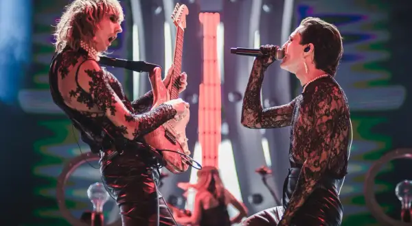 Zespół Måneskin na scenie, wokalista śpiewa, gitarzysta gra na gitarze.
